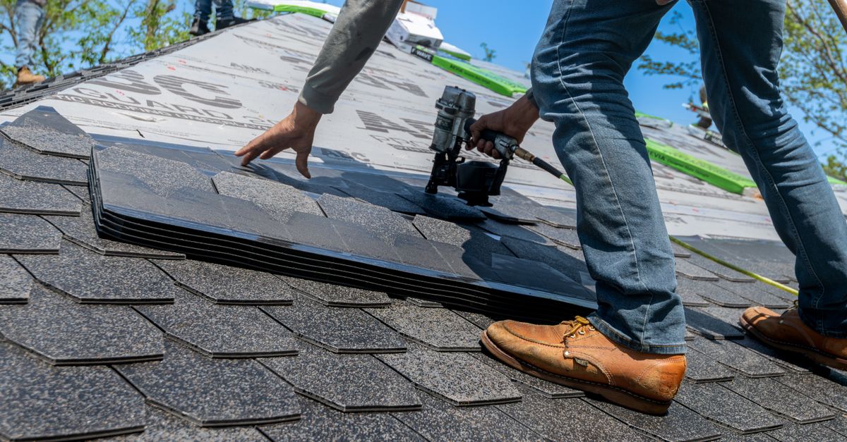 Roofing crew installing asphalt shingles on a residential roof