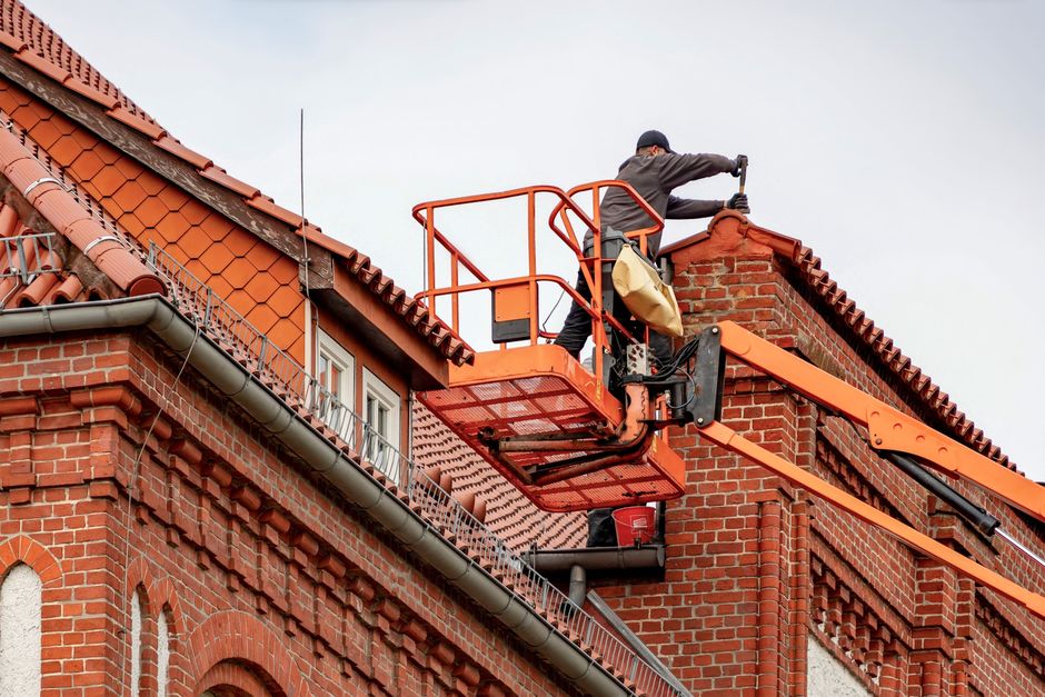 Roofer climbing a ladder to inspect a residential roof